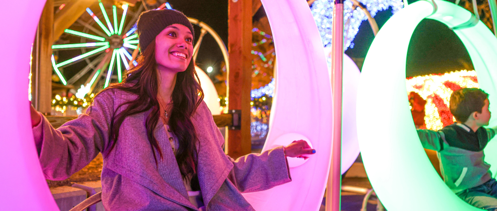 Two girls sitting inside a large Christmas ornament display